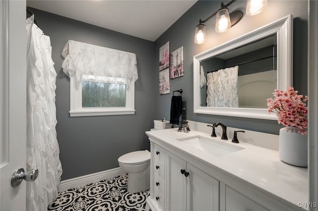 bathroom featuring toilet, a shower with shower curtain, vanity, and baseboards