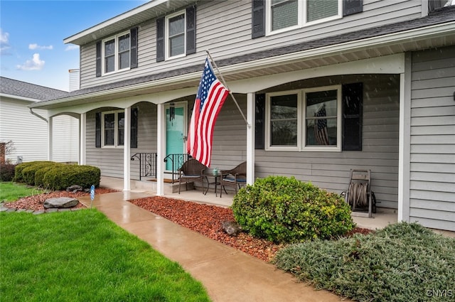 entrance to property featuring a lawn and covered porch