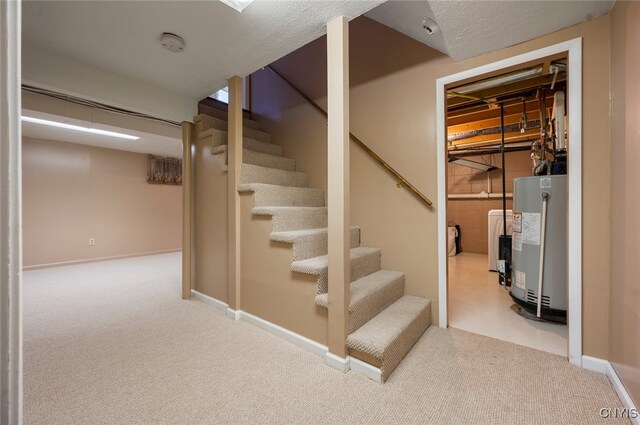 finished basement featuring gas water heater, stairs, carpet floors, and washer / clothes dryer