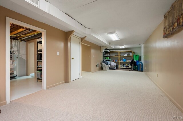 finished basement featuring visible vents, water heater, carpet, and baseboards