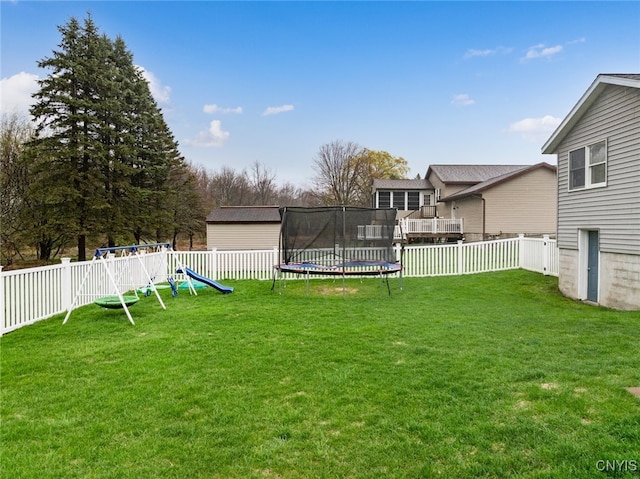 view of yard featuring a trampoline, a playground, and a fenced backyard