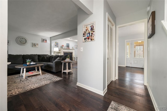 hallway featuring dark wood-style flooring and baseboards