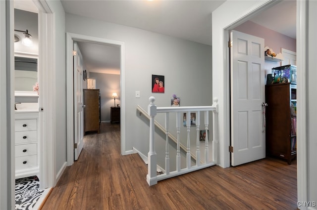 hall featuring dark wood-style floors, an upstairs landing, and baseboards
