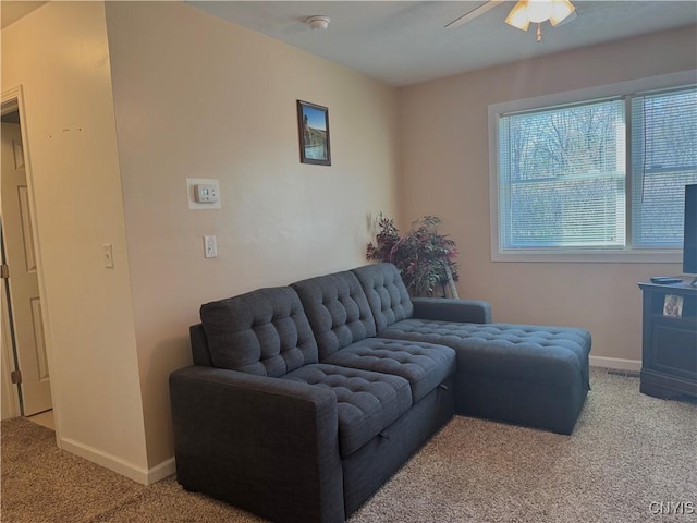 living area with baseboards, ceiling fan, and light colored carpet