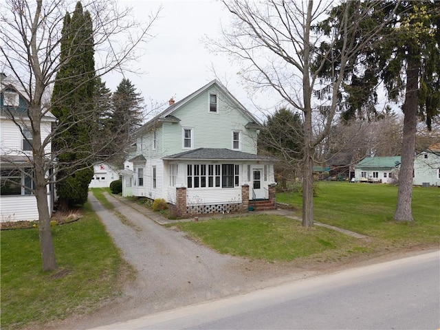 view of front of property with a chimney, entry steps, driveway, roof with shingles, and a front lawn