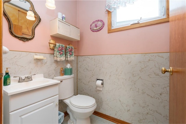 half bath with tile walls, wainscoting, toilet, and vanity