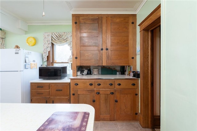 kitchen with ornamental molding, brown cabinets, light countertops, and freestanding refrigerator