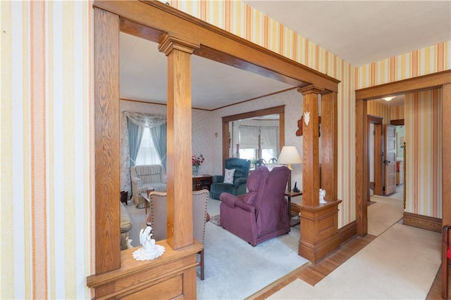 living area with wallpapered walls, decorative columns, and wood finished floors
