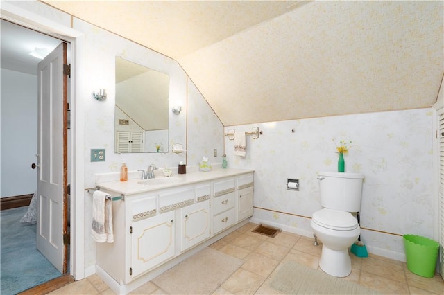 bathroom featuring toilet, vanity, vaulted ceiling, and baseboards
