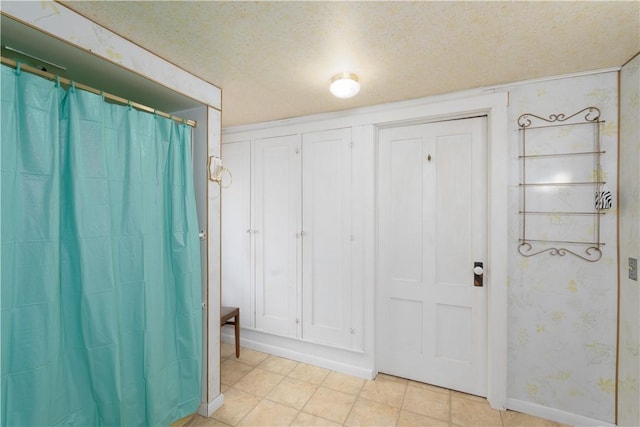 entryway featuring a textured ceiling, wallpapered walls, and baseboards