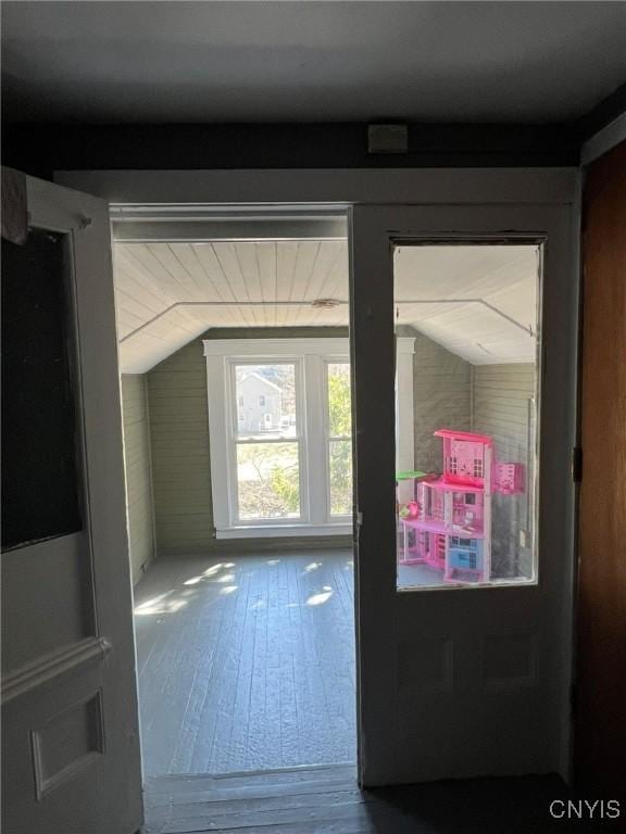 doorway with hardwood / wood-style floors and vaulted ceiling