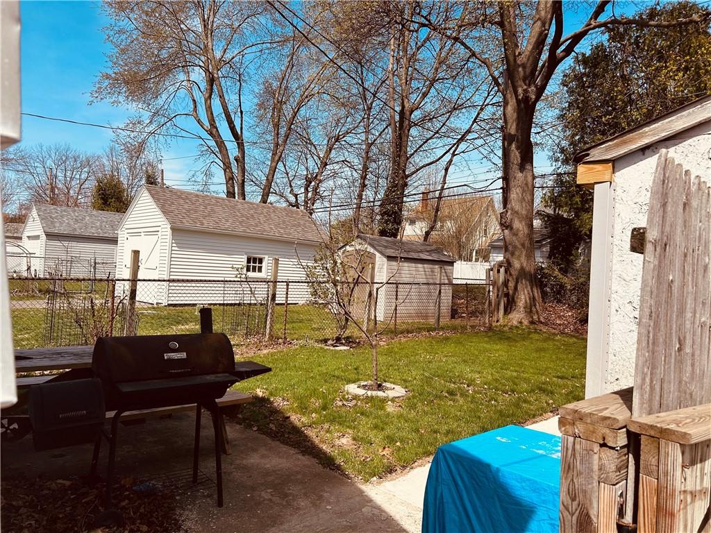 view of yard featuring fence, a storage shed, a patio area, and an outbuilding
