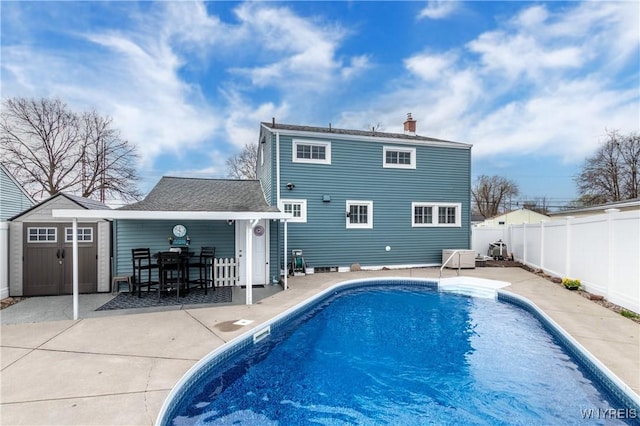 rear view of property with a patio, a fenced in pool, a fenced backyard, and a chimney