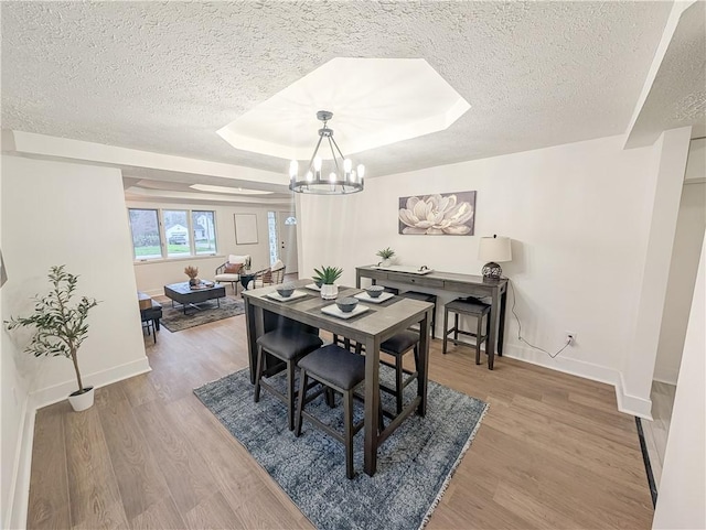 dining area with a chandelier, baseboards, and a textured ceiling