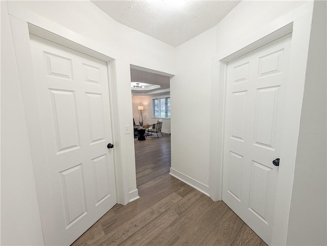 hallway featuring baseboards, a textured ceiling, and dark wood-style flooring