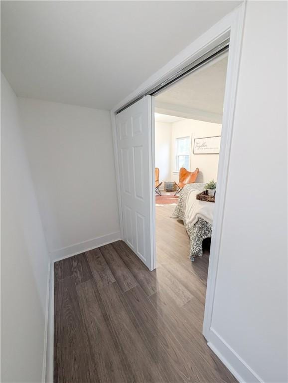 hall with dark wood-style flooring and baseboards