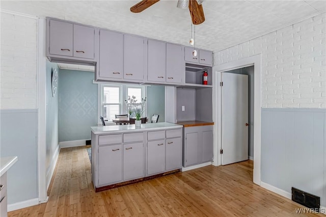 kitchen featuring open shelves, visible vents, light wood-style floors, a peninsula, and a ceiling fan