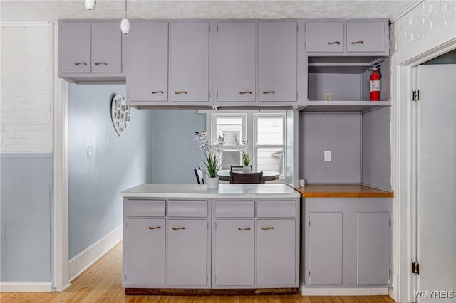 kitchen with light countertops, light wood finished floors, baseboards, and open shelves