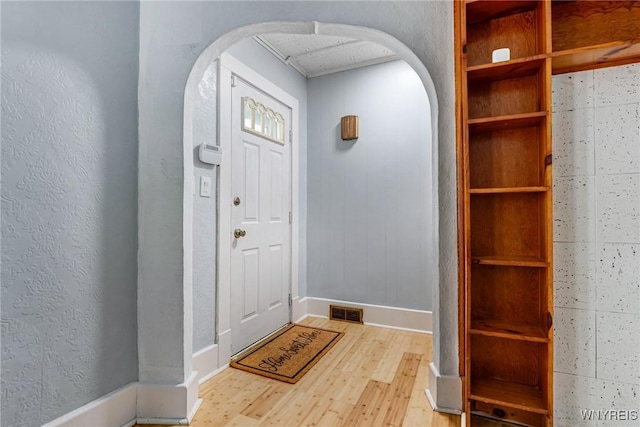 entryway featuring arched walkways, visible vents, wood finished floors, and baseboards
