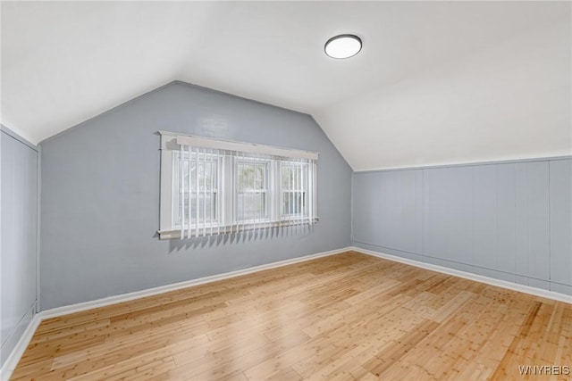 additional living space with wood finished floors, vaulted ceiling, and baseboards