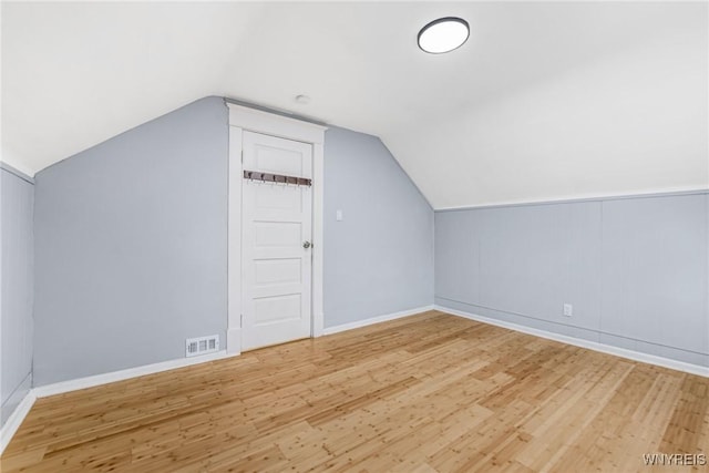 bonus room with lofted ceiling, wood finished floors, visible vents, and baseboards