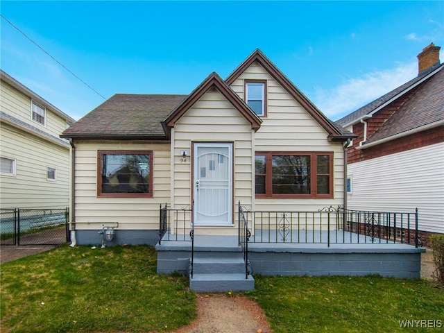 bungalow-style home with fence and a front lawn