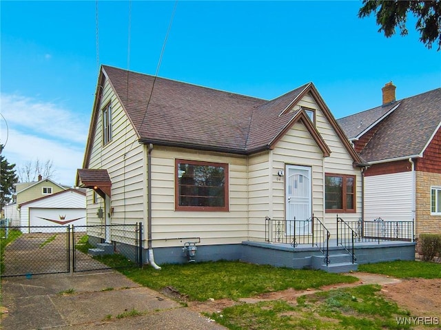 bungalow-style house with a gate, fence, roof with shingles, a detached garage, and a front yard