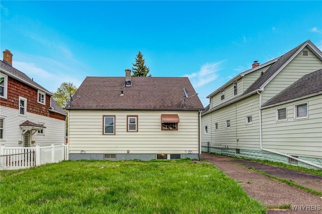 rear view of house featuring a lawn and fence