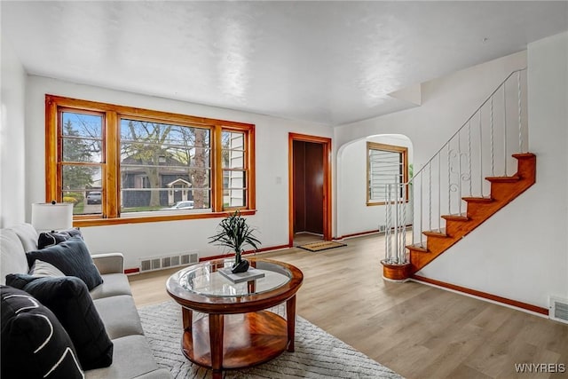 living room with visible vents, wood finished floors, and arched walkways