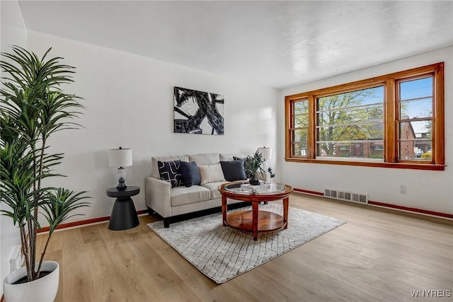 living area with baseboards, visible vents, and light wood-type flooring