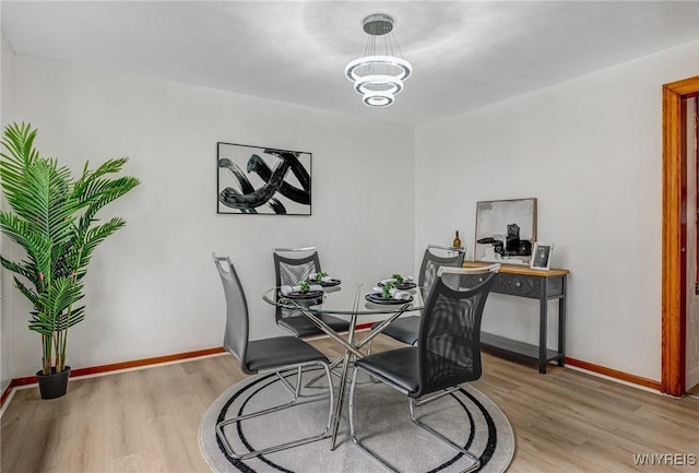 dining room with a notable chandelier, light wood finished floors, and baseboards