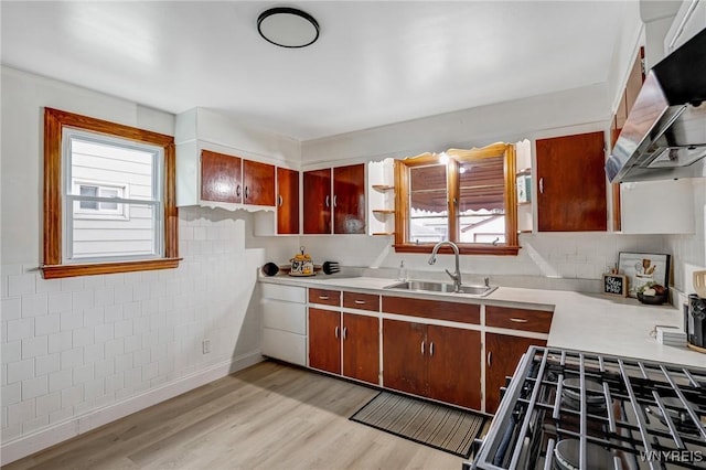 kitchen featuring tile walls, a sink, light wood-style floors, light countertops, and extractor fan