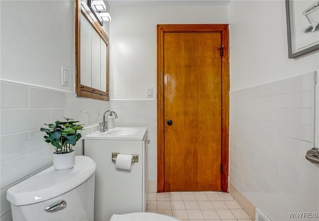 half bathroom featuring tile patterned floors, vanity, toilet, and tile walls