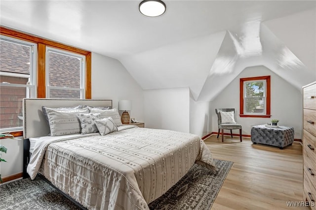 bedroom featuring baseboards, wood finished floors, and vaulted ceiling