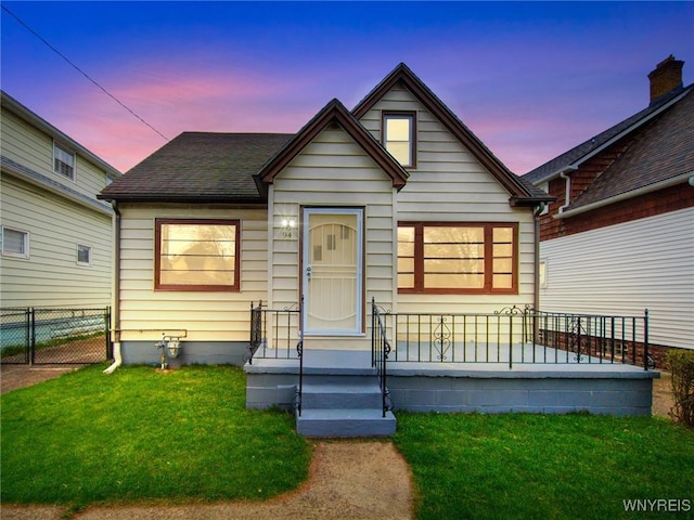 bungalow featuring a front lawn and fence