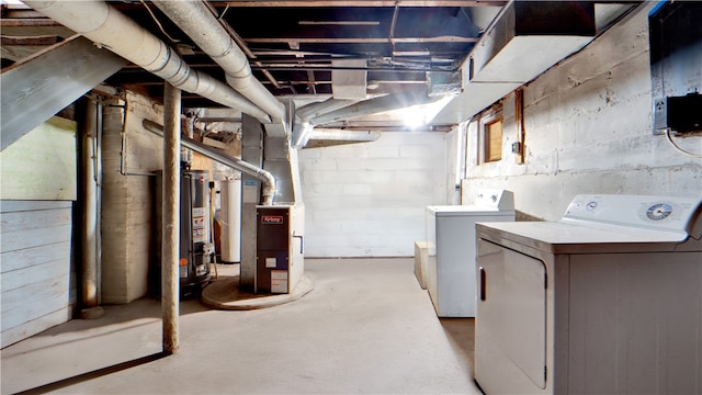 unfinished below grade area featuring heating unit, water heater, and washer and clothes dryer