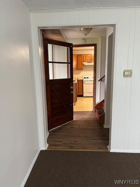 corridor featuring baseboards, wood finished floors, and stairs