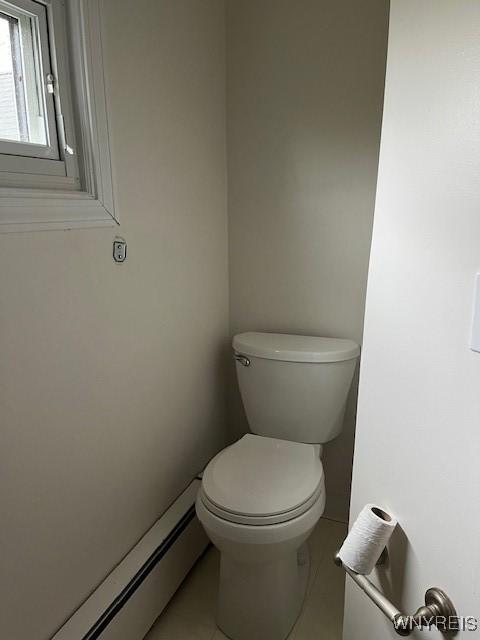 bathroom featuring tile patterned floors, toilet, and a baseboard heating unit