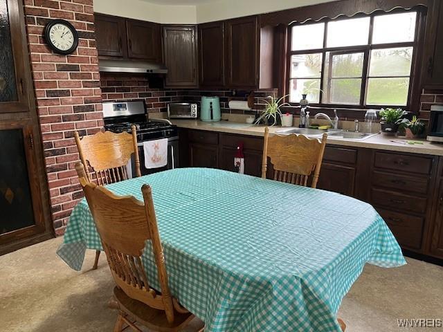 kitchen with stainless steel gas range, dark brown cabinetry, light countertops, and under cabinet range hood