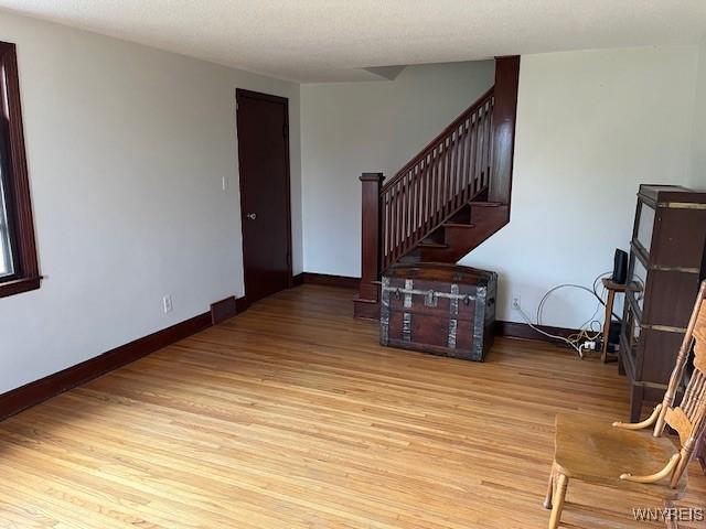living room with stairway, light wood-style flooring, and baseboards