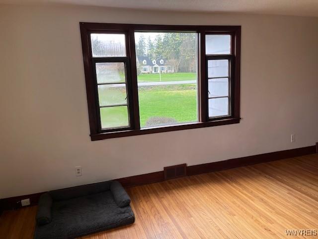 spare room featuring light wood finished floors, visible vents, and baseboards