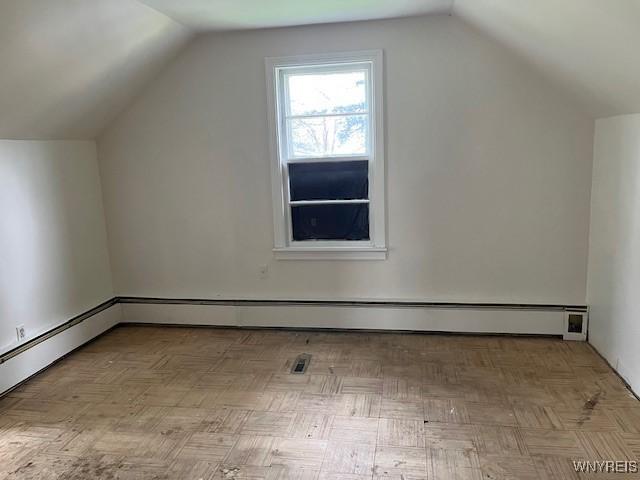 additional living space featuring lofted ceiling and a baseboard heating unit