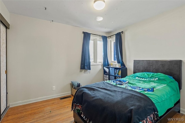 bedroom featuring baseboards, visible vents, and wood finished floors