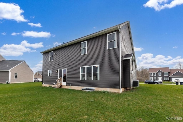 back of house featuring entry steps, central AC unit, and a lawn