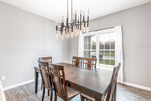 dining room featuring an inviting chandelier, wood finished floors, and baseboards