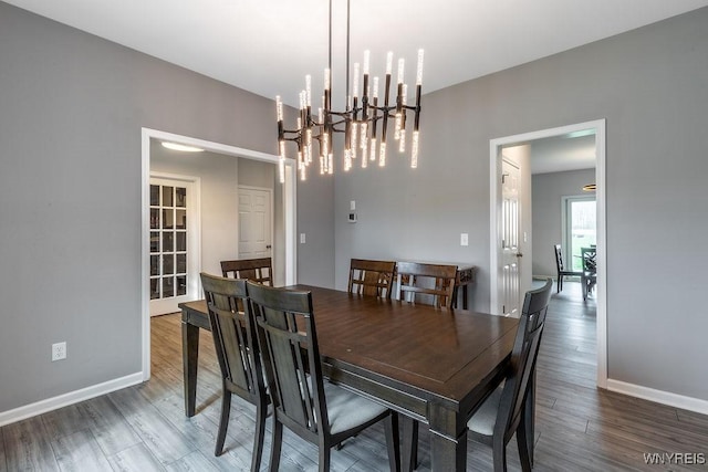dining space with a chandelier, wood finished floors, and baseboards