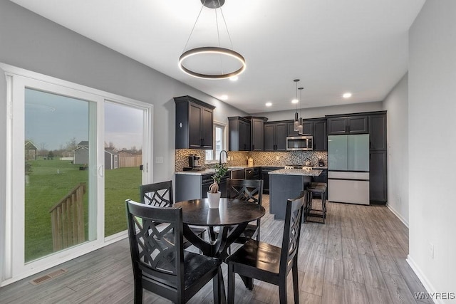 dining space featuring baseboards, visible vents, light wood-style flooring, and recessed lighting