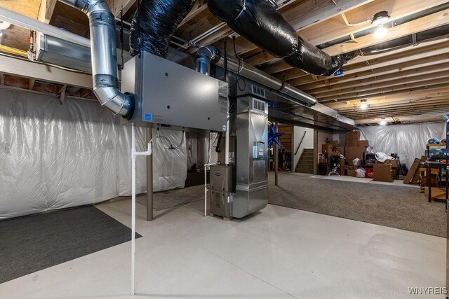 unfinished basement with heating unit, visible vents, and stairway