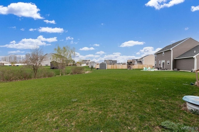 view of yard with a residential view, a storage unit, an outbuilding, and fence
