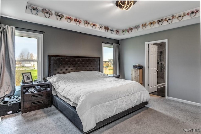 bedroom featuring baseboards, connected bathroom, multiple windows, and carpet flooring